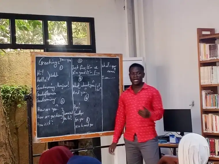 Animateur du CDE devant un tableau noir portant une leçon d'anglais