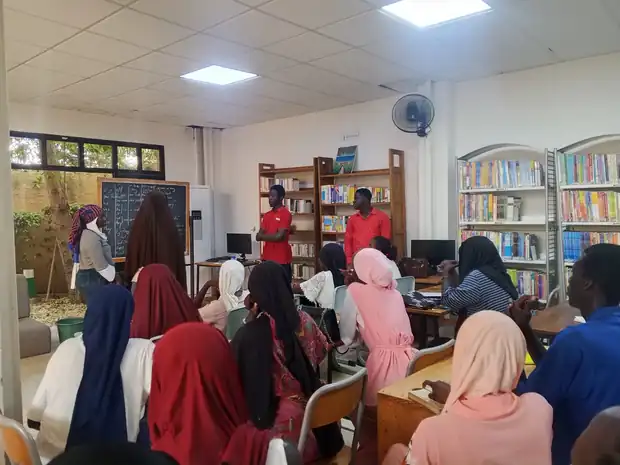 Salle pleine d'apprenants écoutant deux animateurs