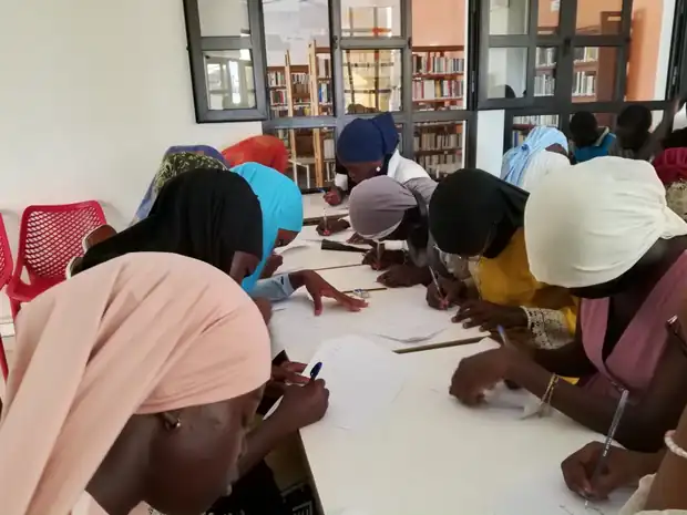 Apprenants réunis autour d'une table en train d'écrire